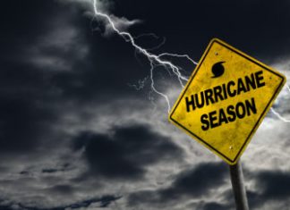 Hurricane season with symbol sign against a stormy background and copy space. Dirty and angled sign adds to the drama.