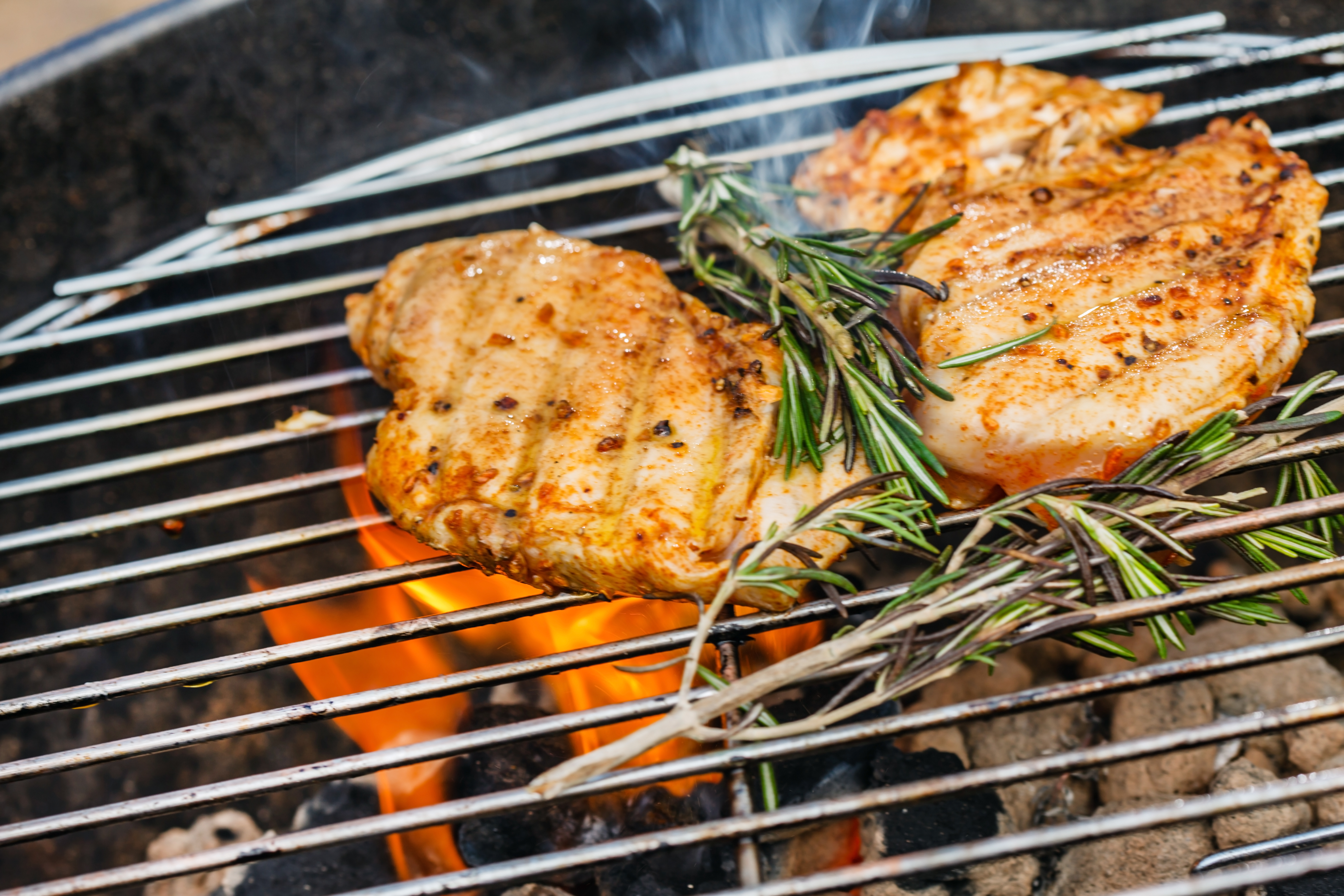 chicken cooking on grill with herbs