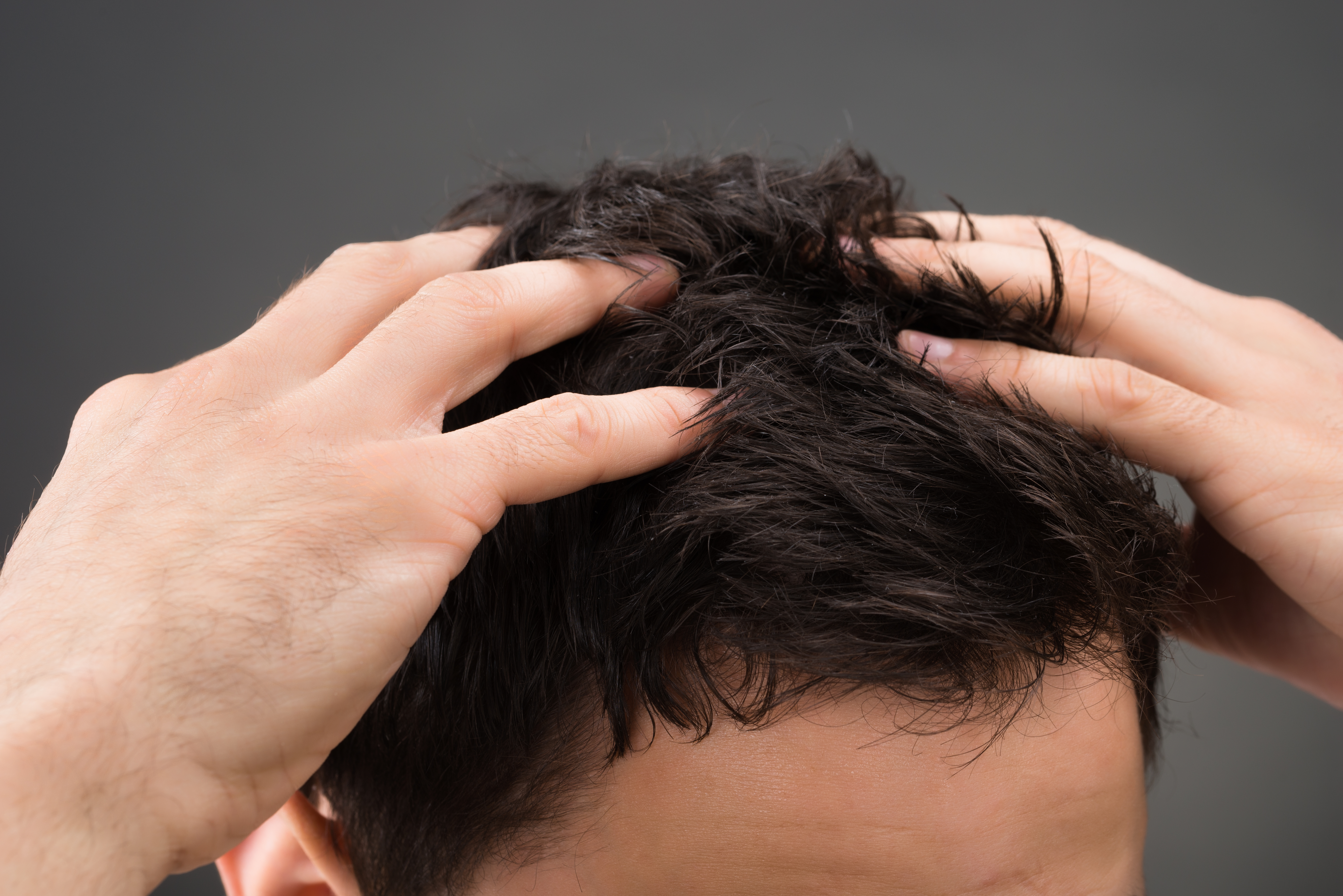 Cropped image of man suffering from dandruff against gray background