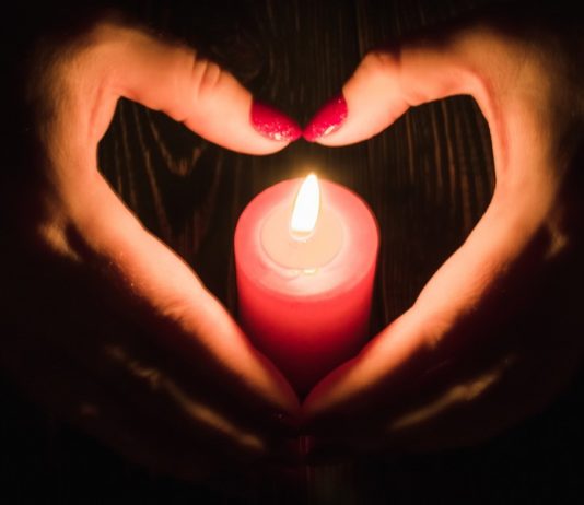 Heart Shaped Female Hands Around Burning Red Candle