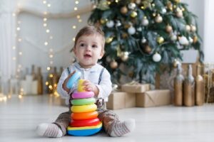 The Kid, Sitting On The Floor Near A Smart Christmas Tree, Collects A Multicolored Pyramid.