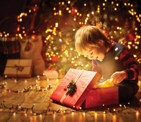 Christmas Child Open Present Gift, Happy Baby Boy Looking To Magic Light In Box, Kid And Xmas Tree