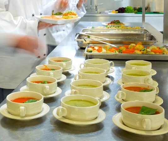 Four,chefs,working,in,a,modern,kitchen,preparing,soups