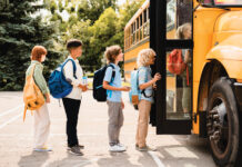 Multiethnic Mixed Race Pupils Classmates Schoolchildren Students Standing In Line Waiting For Boarding School Bus Before Starting New Educational Semester Year After Summer Holidays