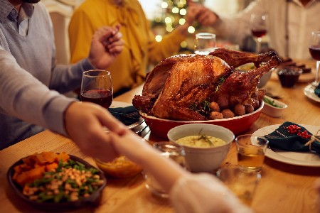 Close Up Of Family Saying Grace During Thanksgiving Meal At Dining Table.