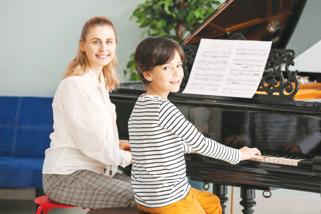 Private Music Teacher Giving Piano Lessons To Little Boy