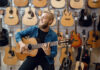 Young Man Plays On Acoustic Guitar In Music Store