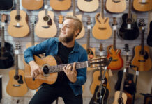 Young Man Plays On Acoustic Guitar In Music Store