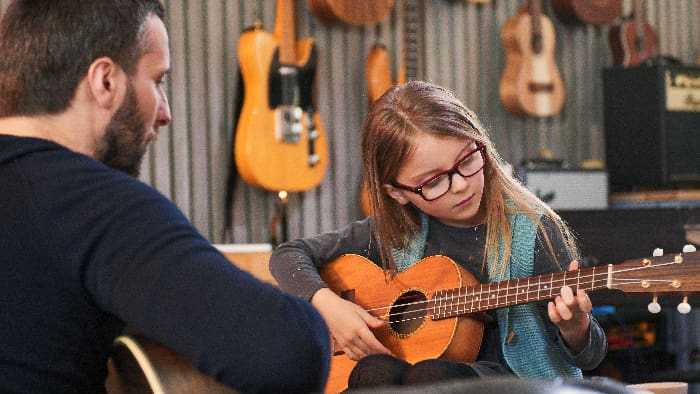 Dad,teaching,guitar,and,ukulele,to,his,daughter.little,girl,learning
